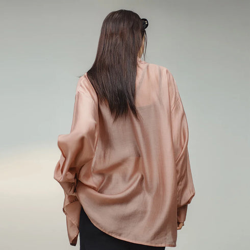Person wearing a light pink satin blouse against a neutral background